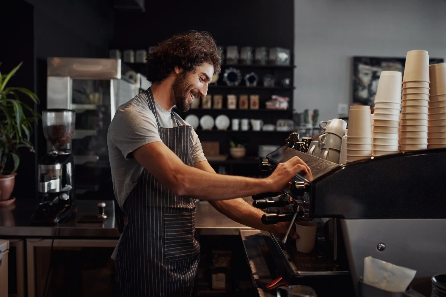 Tress Kaffee, Lächelnder Mann mit Schürze bereitet Kaffee für Kunden zu