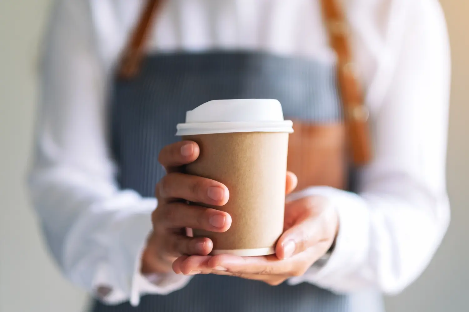 Tress Kaffee, Eine Kellnerin hält und serviert einen Pappbecher mit heißem Kaffee in einem Café
