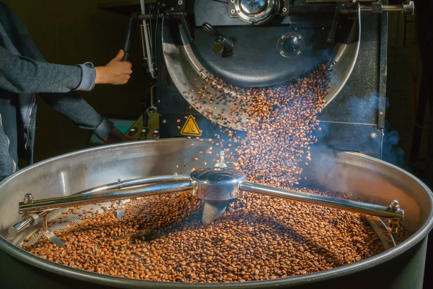Tress Kaffee, Professioneller männlicher Röster, der die Maschine mit Kaffeebohnen belädt